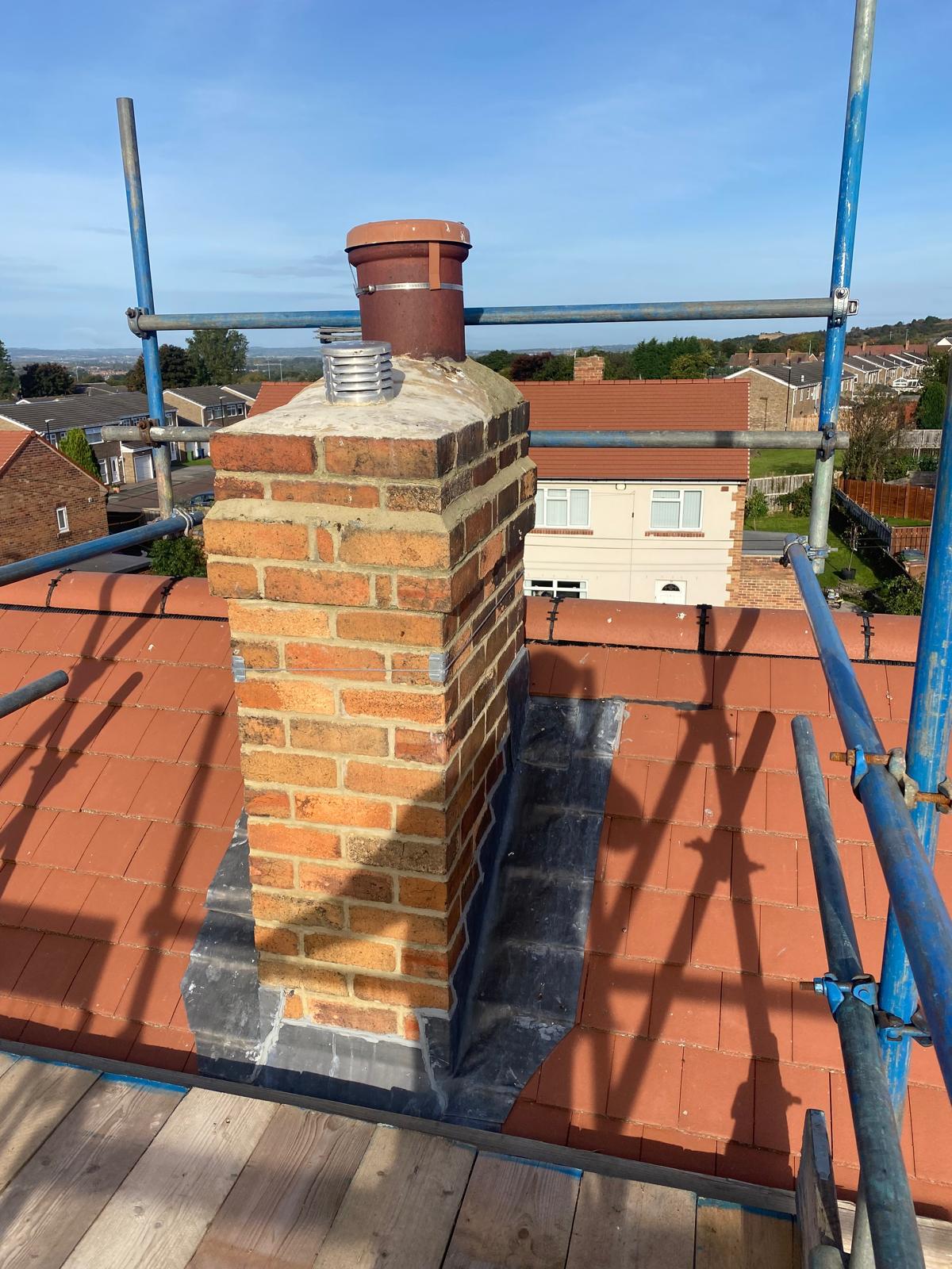 New lead flashing and repointing around a brick chimney stack on a red tiled roof